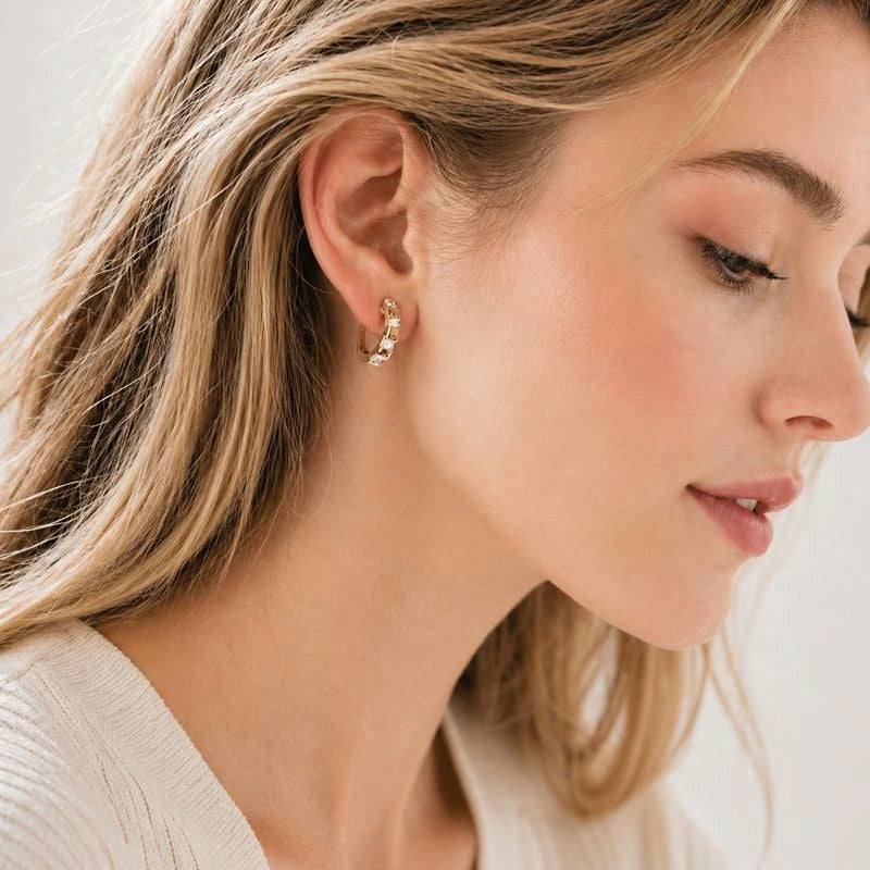 Close-up of a woman wearing 16k gold cubic zirconia earrings with a neutral background