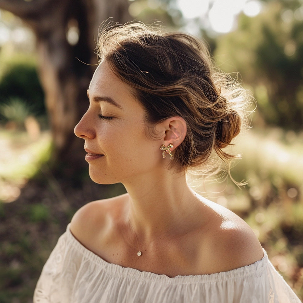 woman wearing tiny gold bow clip-on earrings. Simple and sweet for everyday wear. Hinge back closure for non pierced ears. Embrace the lessismore jewelry trend.