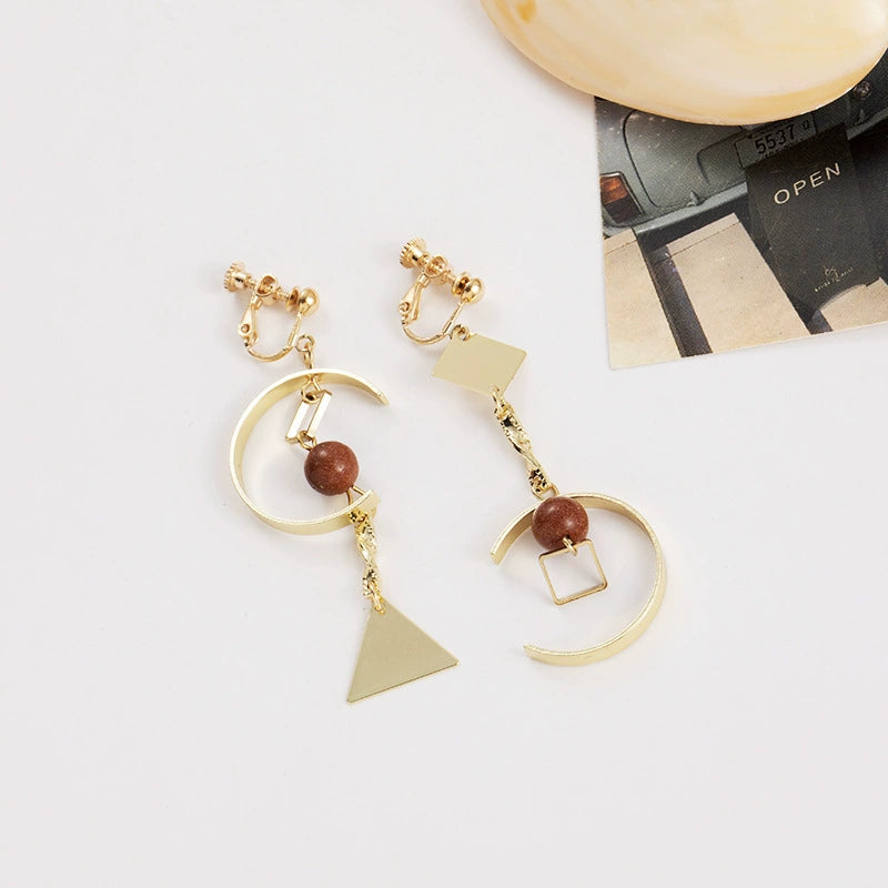 Close-up of modern fake earrings with gold-plated geometric shapes
