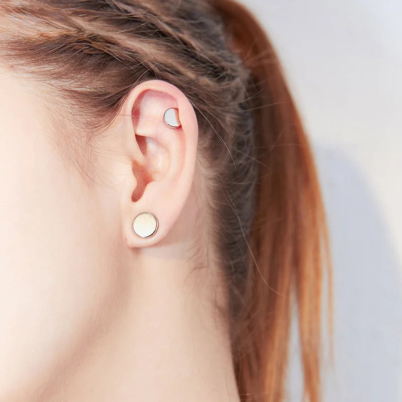 A woman showcasing a minimalist style, accenting her look with a stainless steel matte silver magnetic ear stud.