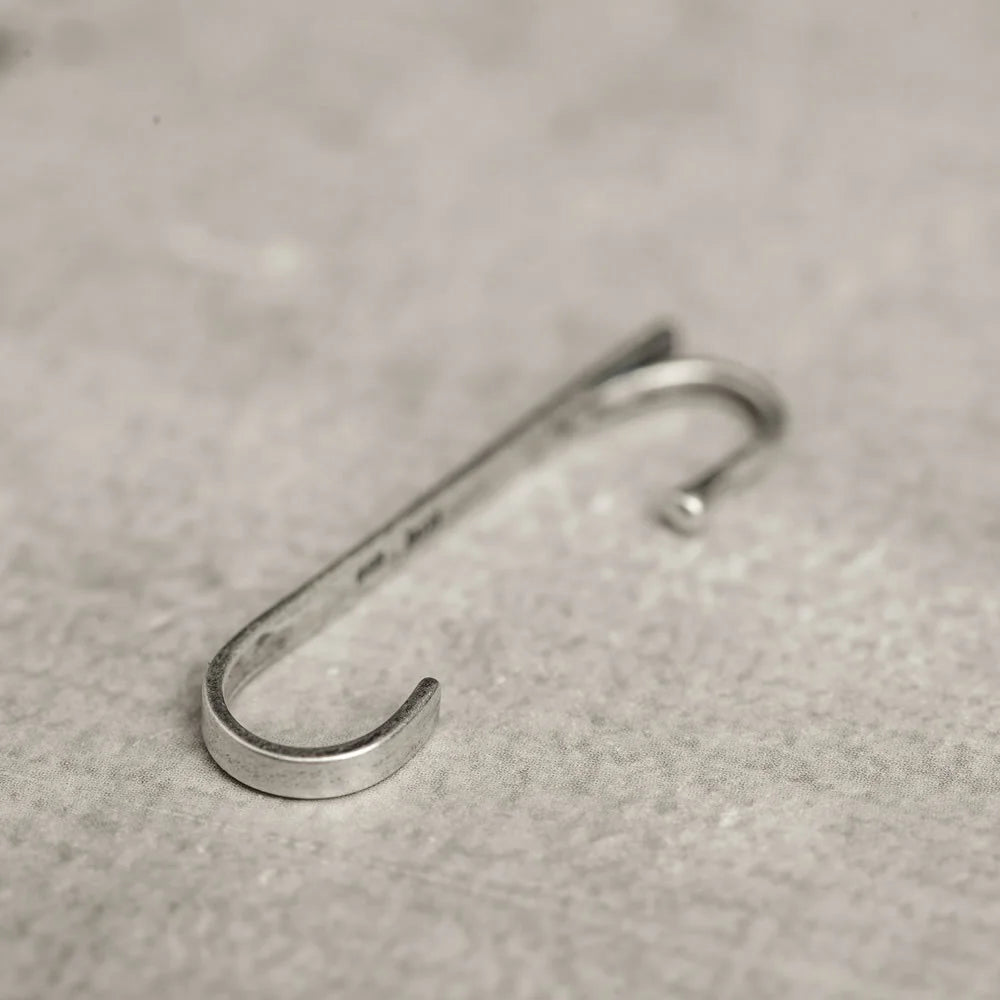 Side angle view of the Axis sterling silver ear cuff, showing its hook detail and brushed metal texture.