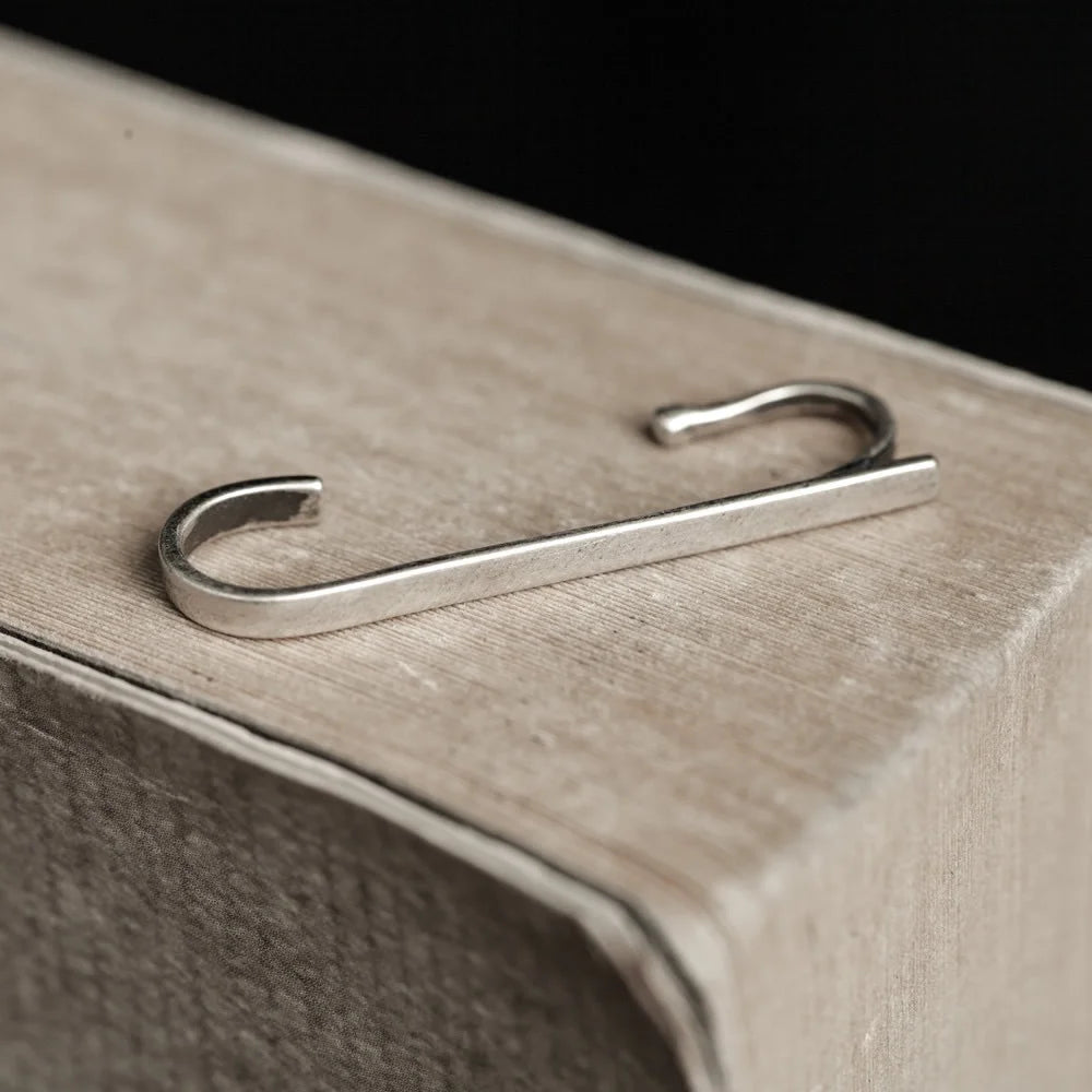 The Axis sterling silver minimalist wrap ear cuff resting on the textured surface.