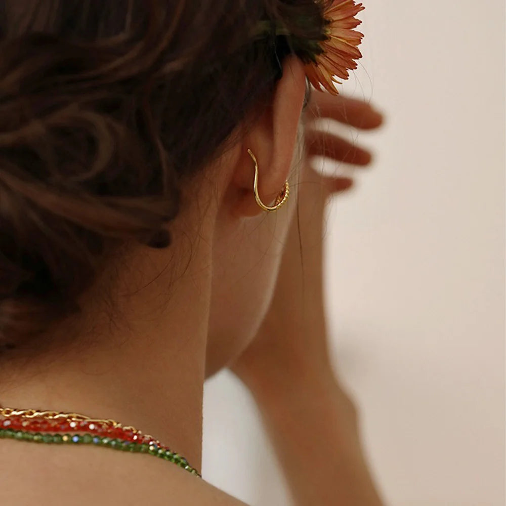 Back view of a model wearing the clip-on twisted rope gold ear cuff, showing how it securely hooks onto the ear.