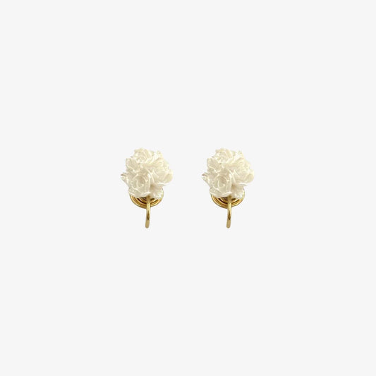 A pair of dainty white flower clip-on earrings with gold-tone mosquito coil backs, shown isolated on a white background.