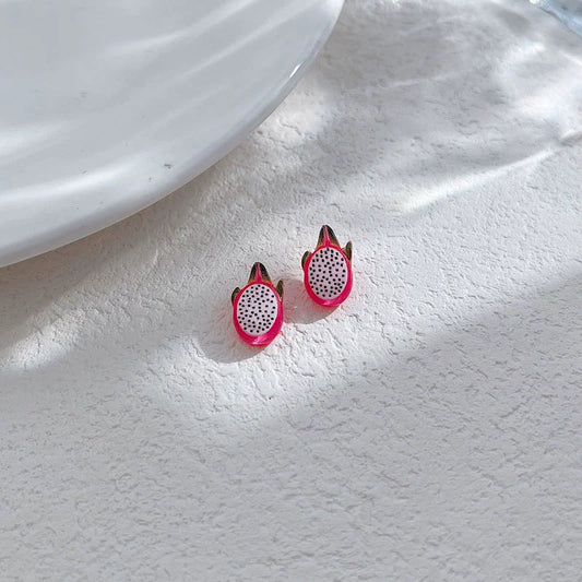 Two vibrant pink pitaya magnetic stud earrings displayed on a white textured surface under soft natural sunlight.