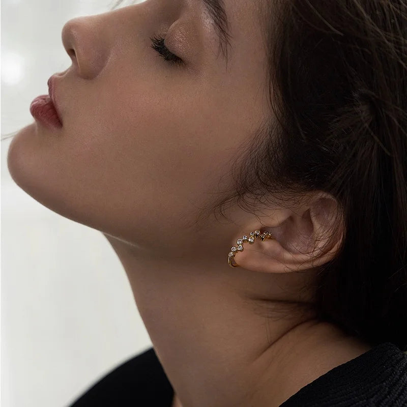 Side profile of a model wearing the elegant clip-on gold zircon ear cuff to create a sophisticated, non-pierced ear stack.