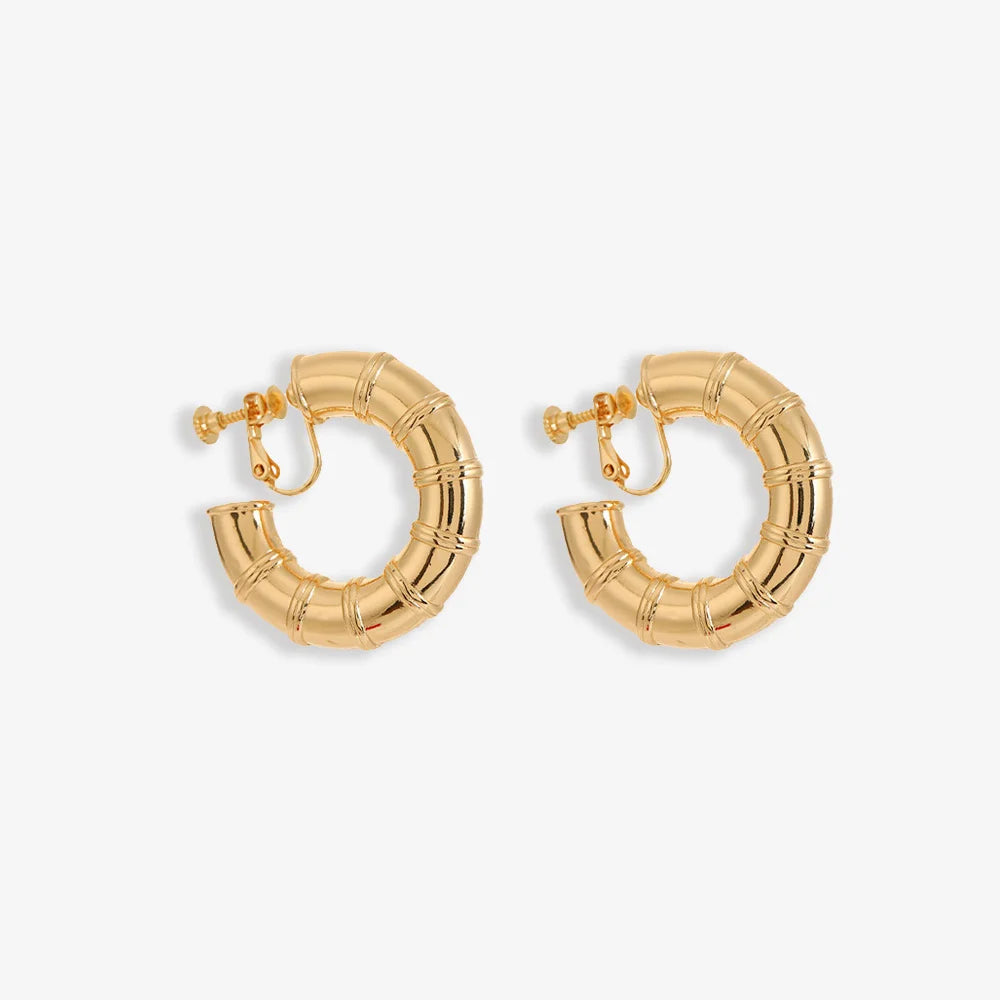 A pair of gold bamboo hoop clip-on screw back earrings on a white background