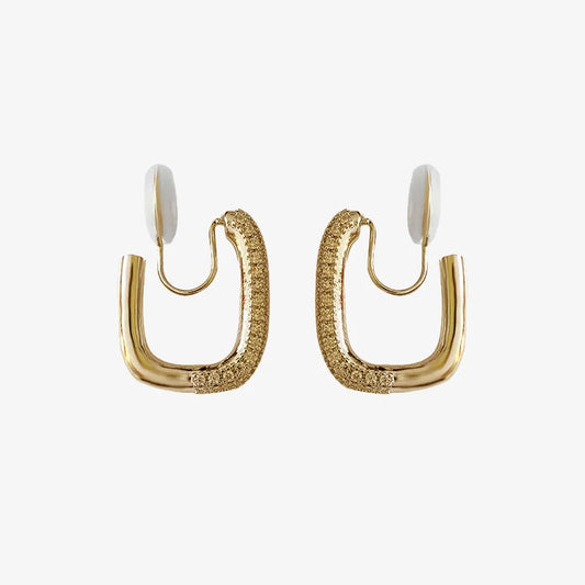 A pair of gold pavé square clip-on hoop earrings with white comfort pads, shown on a white background.