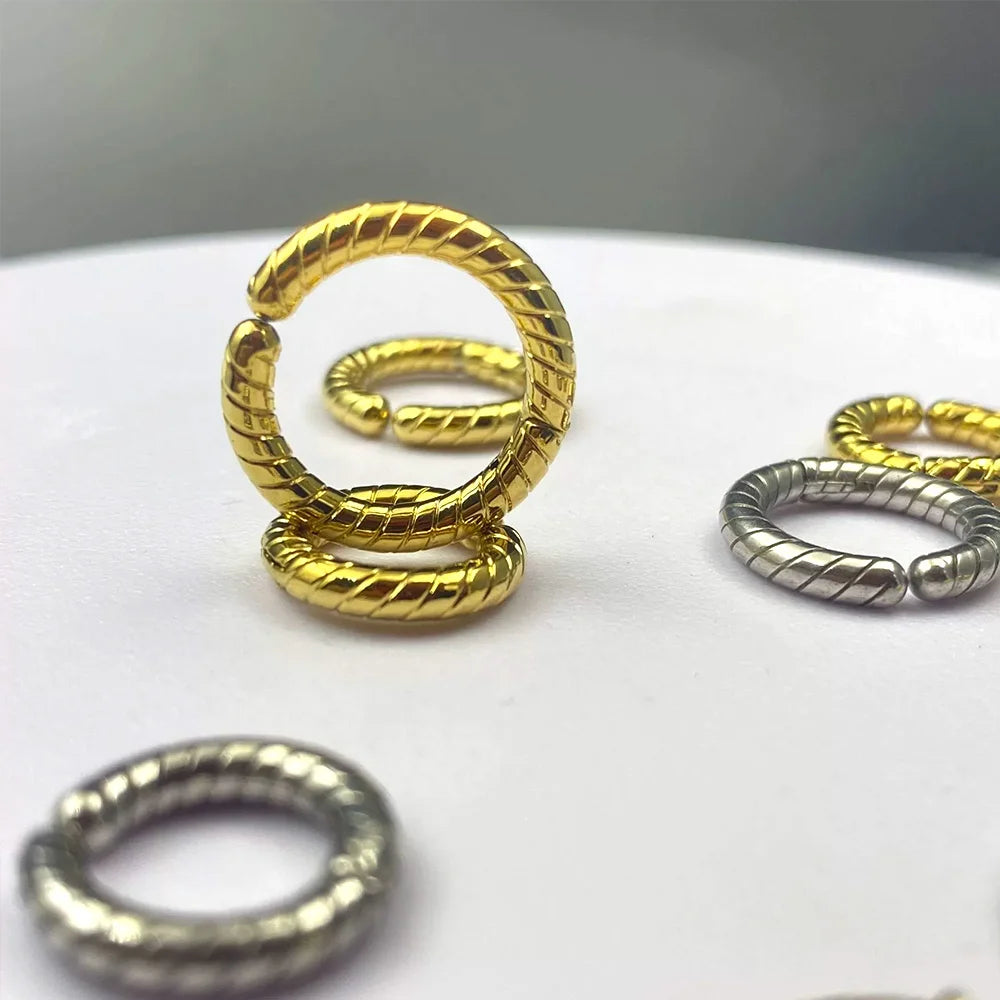 Two gold twisted rope clip-on hoop earrings interlinked, showcasing the seamless spring closure and textured detail.