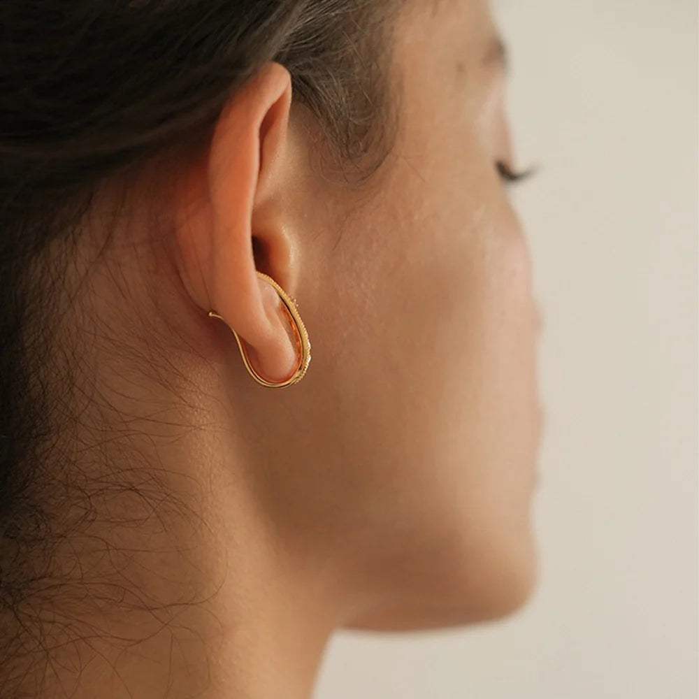 View from behind of a model showing how the gold filigree ear cuff wraps securely around the ear.