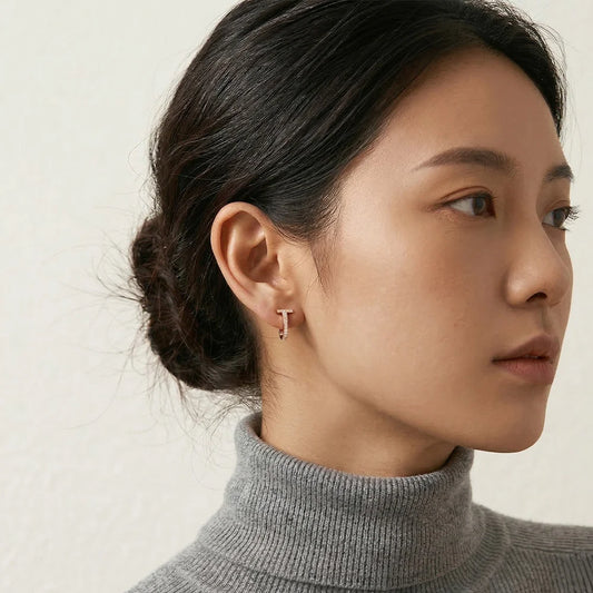 A stylish woman wearing the rose gold T-motif clip-on earrings, showcasing the elegant fit and designer inspired jewelry look.