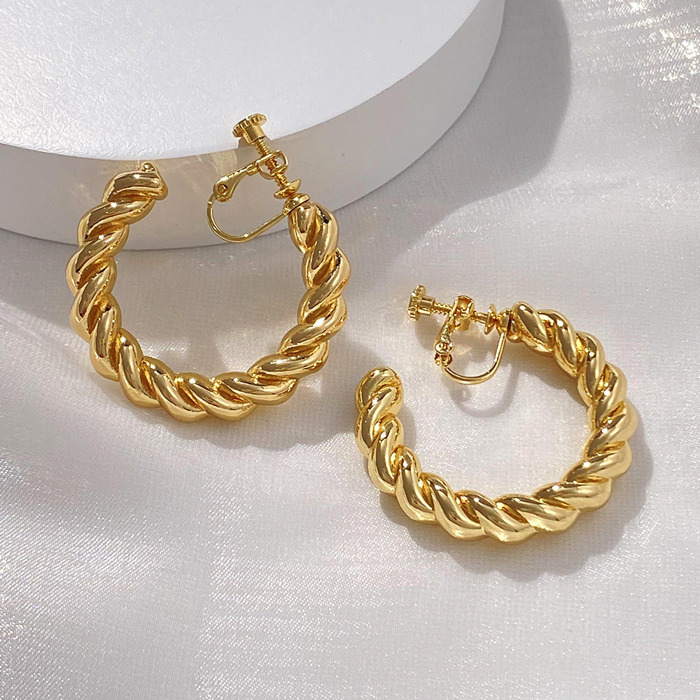 Chunky Gold Hoops with a Twist. These statement clip-on earrings in gold feature a unique twisted design for a touch of modern flair. Secure screw-back closure for comfort. Elevate your everyday look with a bold touch.