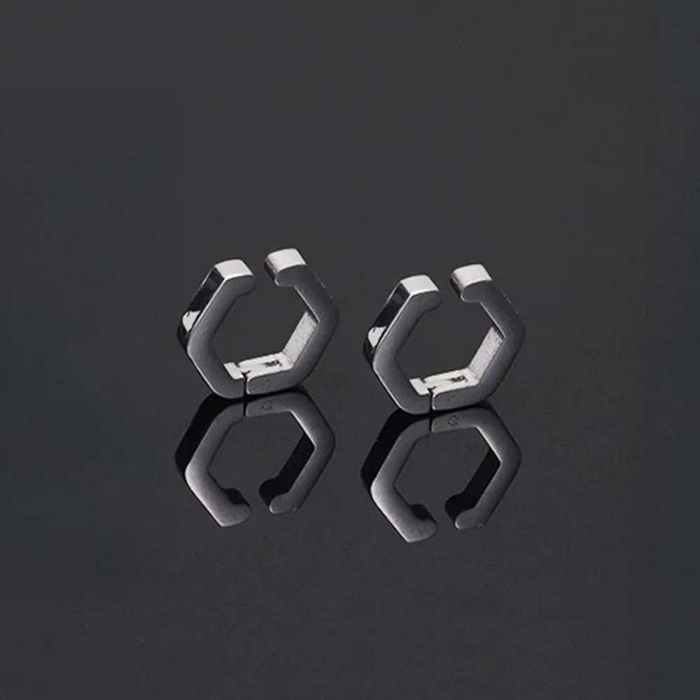 A stylish product shot of the men's titanium steel clip-on huggie earrings in silver on a reflective black surface.
