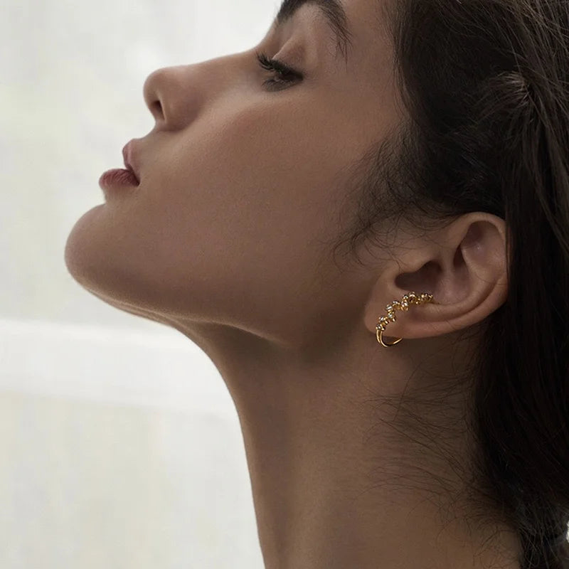 A model showcasing the elegant Aura gold zircon lobe cuff, demonstrating how it comfortably sits on the ear.