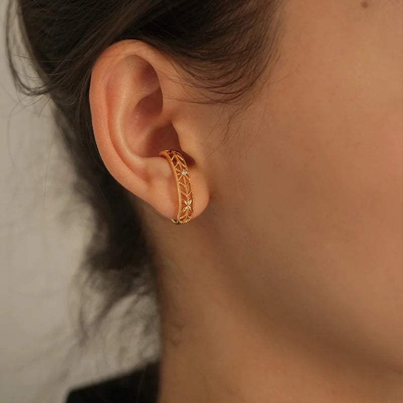 A model wearing the intricate floral filigree gold ear cuff on the lobe cartilage of her ear.
