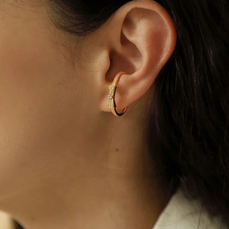 A model wearing the dainty gold ear cuff with a crystal bow on the conch of her ear.