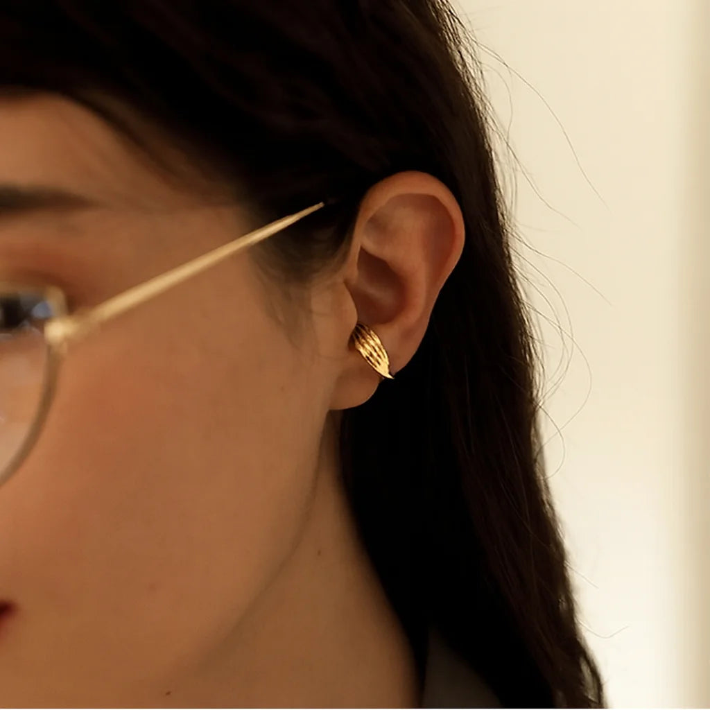 Model wearing the wide gold ear cuff on the conch of her ear for a chic, minimalist look.