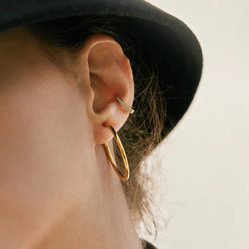Close-up of a model wearing the Stardust pavé gold cuff on her cartilage, paired with a simple gold hoop earring.