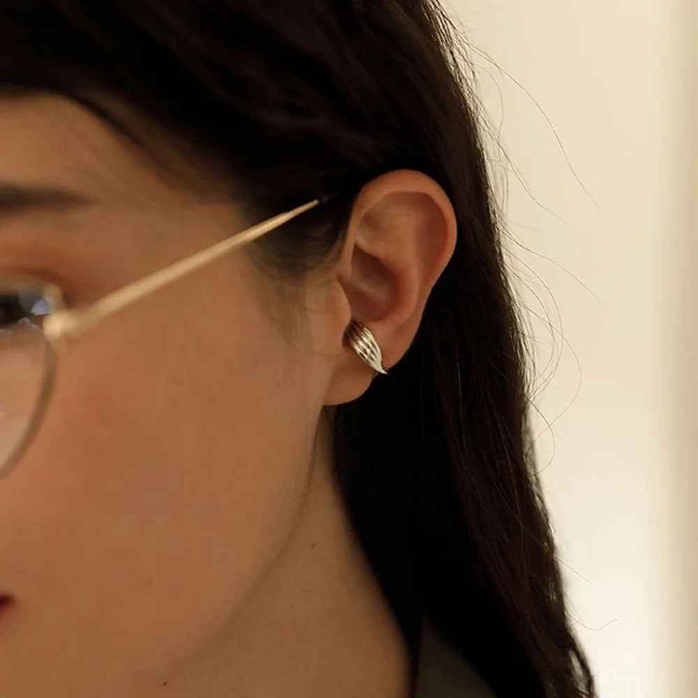 A model wearing the silver twisted band mini ear cuff on the conch part of her ear for a minimalist, modern look.