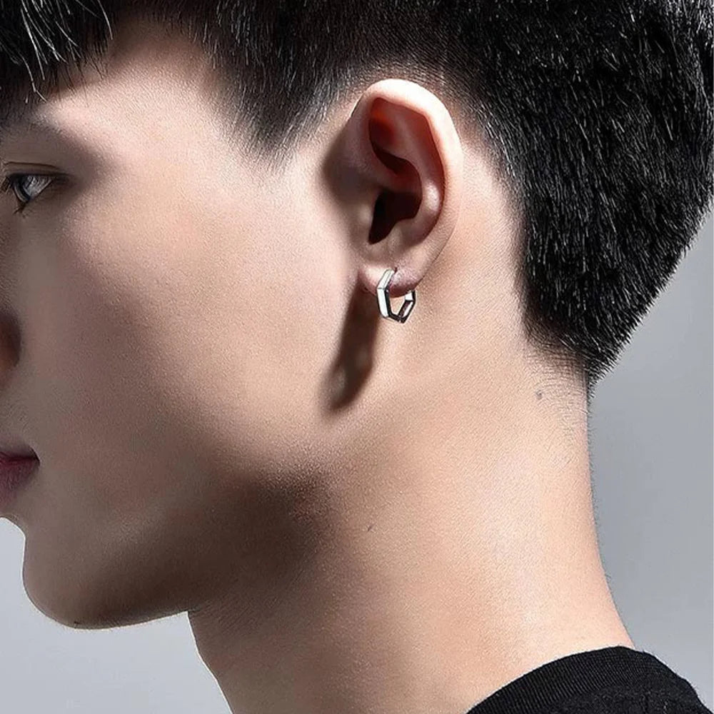 A close-up side profile of a model wearing a single silver hexagon clip-on earring on his earlobe for a minimalist, non-pierced look.