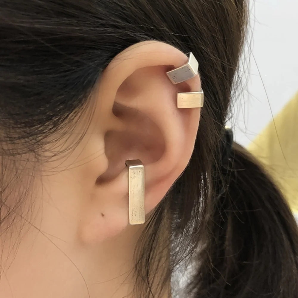 A model showcasing a curated ear stack with three geometric bar ear cuffs placed on the helix, cartilage, and conch.