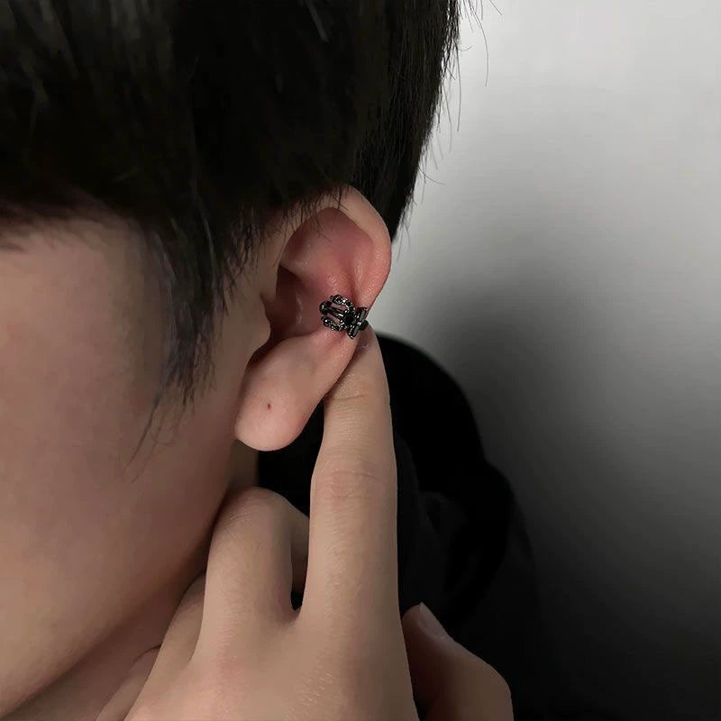A close-up of a model wearing the Shadow Trident black zirconia clip-on ear cuff on the upper ear, highlighting its edgy design.