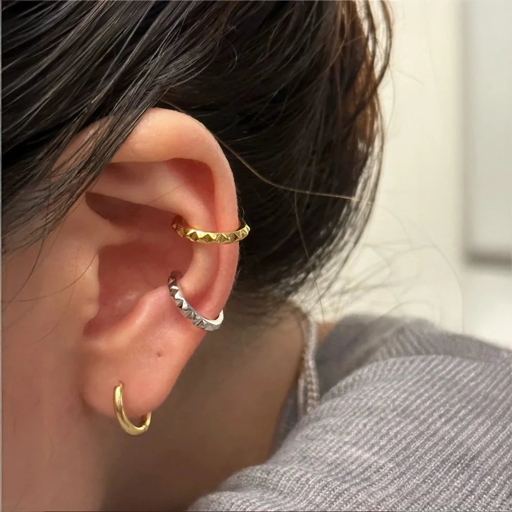Model showcasing a curated ear stack, wearing the gold studded cuff on her helix and the silver studded cuff on her conch.