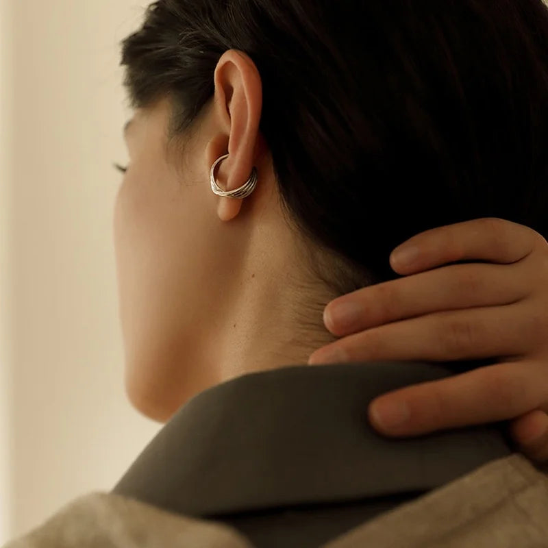 A view from behind of a model wearing the twist silver mini band ear cuff comfortably on her conch.