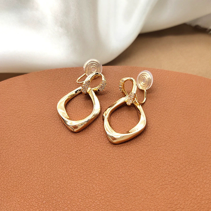 The back view of the gold geometric drop earrings, clearly showing the comfortable and adjustable mosquito coil clip-on mechanism with its silicone pad.