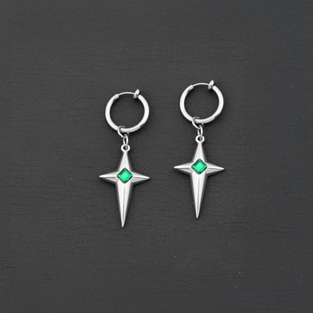 A pair of silver clip-on hoop earrings featuring a dangling four-pointed star charm with a vibrant green gem in the middle, shown on a black surface.