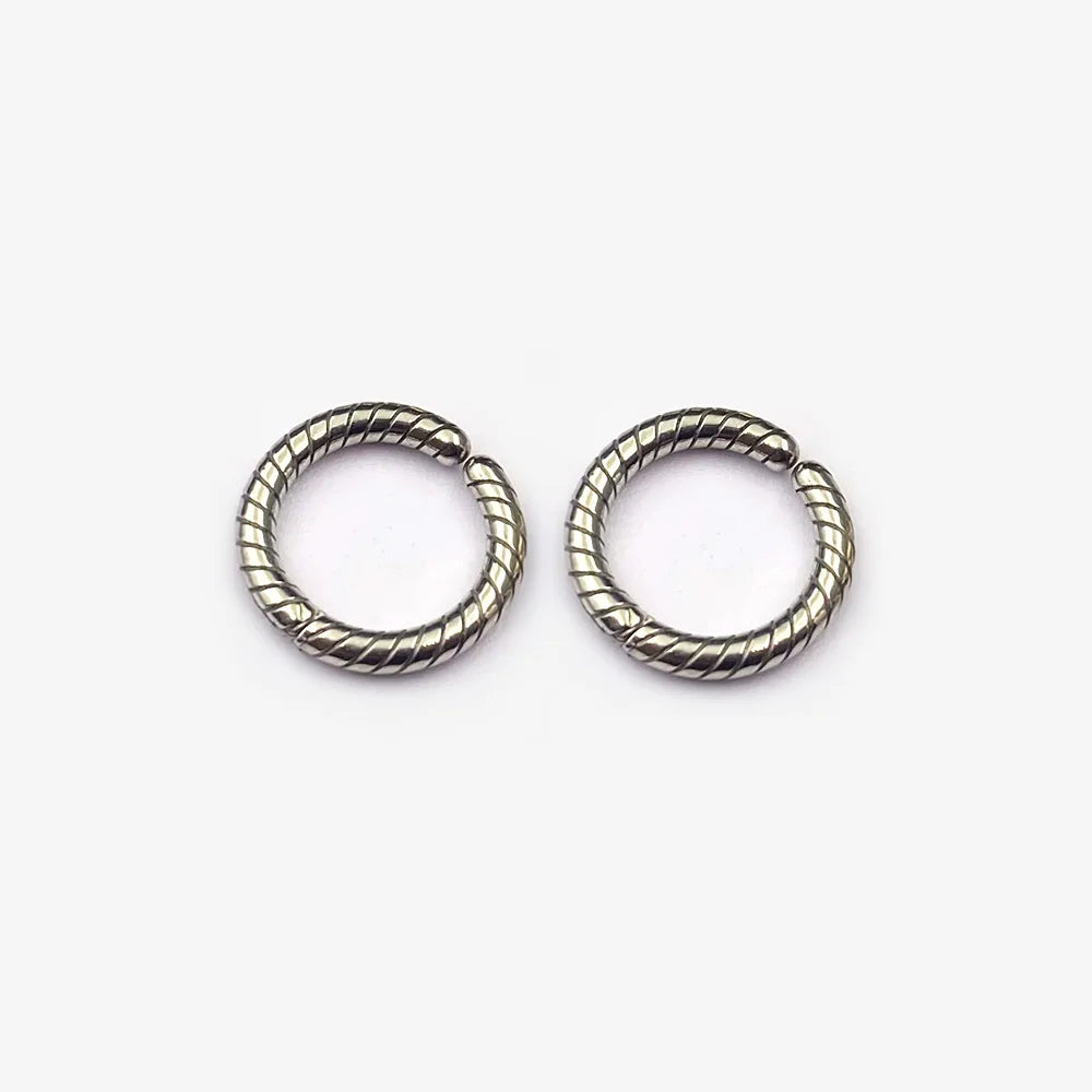 A pair of twisted rope textured clip-on hoop earrings in a polished silver finish, shown isolated on a white background.