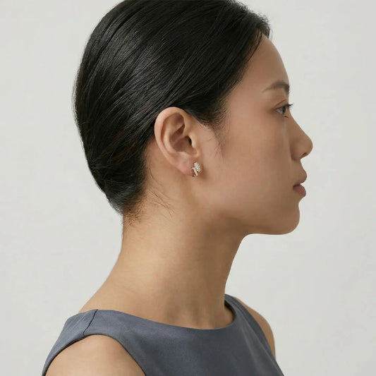 Model wearing sculptural ellipse pavé huggie earrings in 14K rose gold, showcasing the architectural fit and brilliant shining stones.