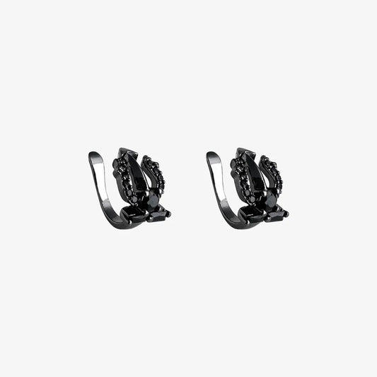 A pair of Shadow Trident black clip-on ear cuffs with black cubic zirconia stones, displayed on a white background to show detail.