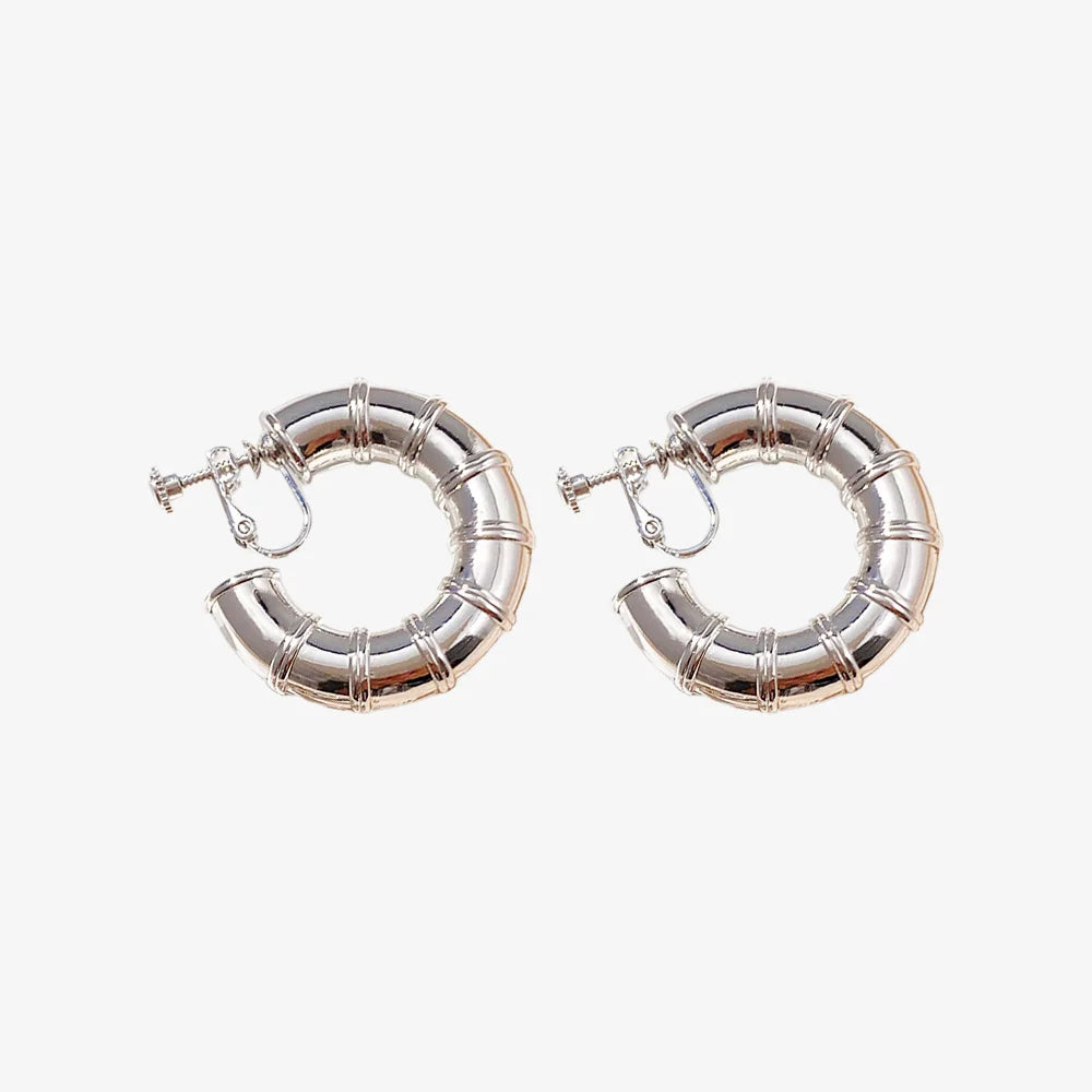 A pair of silver bamboo hoop clip-on earrings with a screw-back mechanism.
