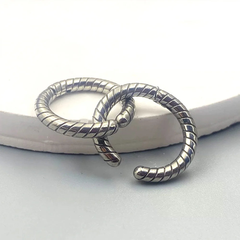 Two silver twisted rope clip-on hoop earrings interlinked, showcasing the seamless spring closure and textured detail.