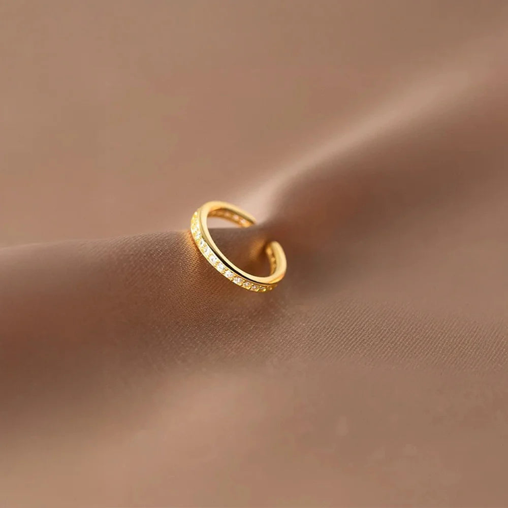 Sparkling pavé gold ear cuff displayed on a piece of satin fabric, highlighting its lustrous finish and brilliant stones.