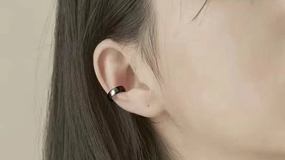 Bold Black Conch Ear Cuff worn on the ear, a glossy black band wrapped around the conch, no piercing required