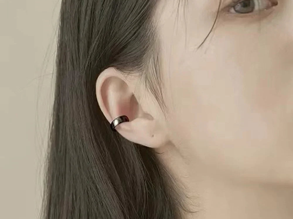 Bold Black Conch Ear Cuff worn on the ear, a glossy black band wrapped around the conch, no piercing required