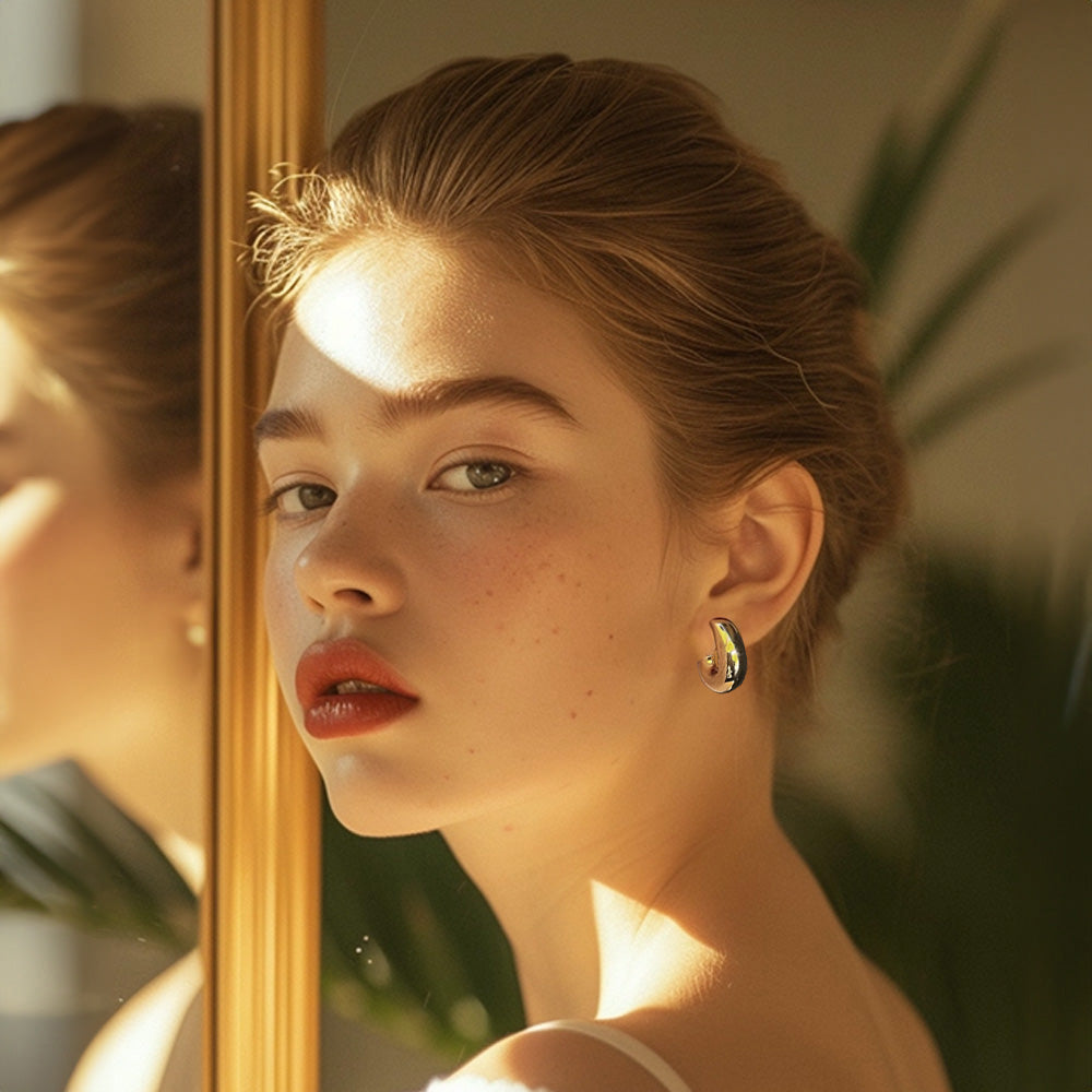 Reflective gold-tone bold hoop clip-on earrings with a modern twist, crafted from a copper alloy. These huggie-style earrings are secured with a screw-back closure, adding a dash of elegance to any look.