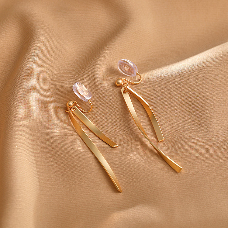 Gold ribbon clip-on earrings add a touch of sophisticated style. The sleek, minimalist design creates a modern and eye-catching look. Crafted from gold-tone copper alloy with a coil clip closure for comfortable wear, even for non-pierced ears. 