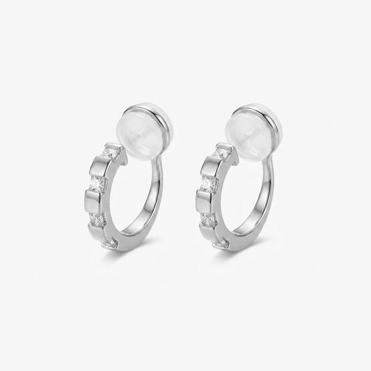 Front view of a pair of 16k white gold plated huggie clip on earrings with sparkling baguette cubic zirconia.