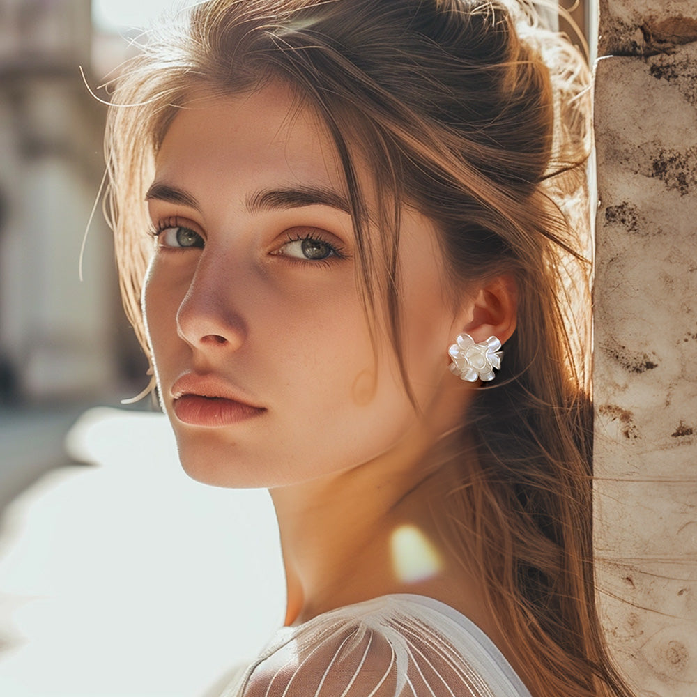 A bride wearing White Flower Clip-On Earrings. Their pristine white color, crafted from resin and alloy, forms a delicate floral design. The hinged-back closure ensures a comfortable fit for all-day wedding celebrations.