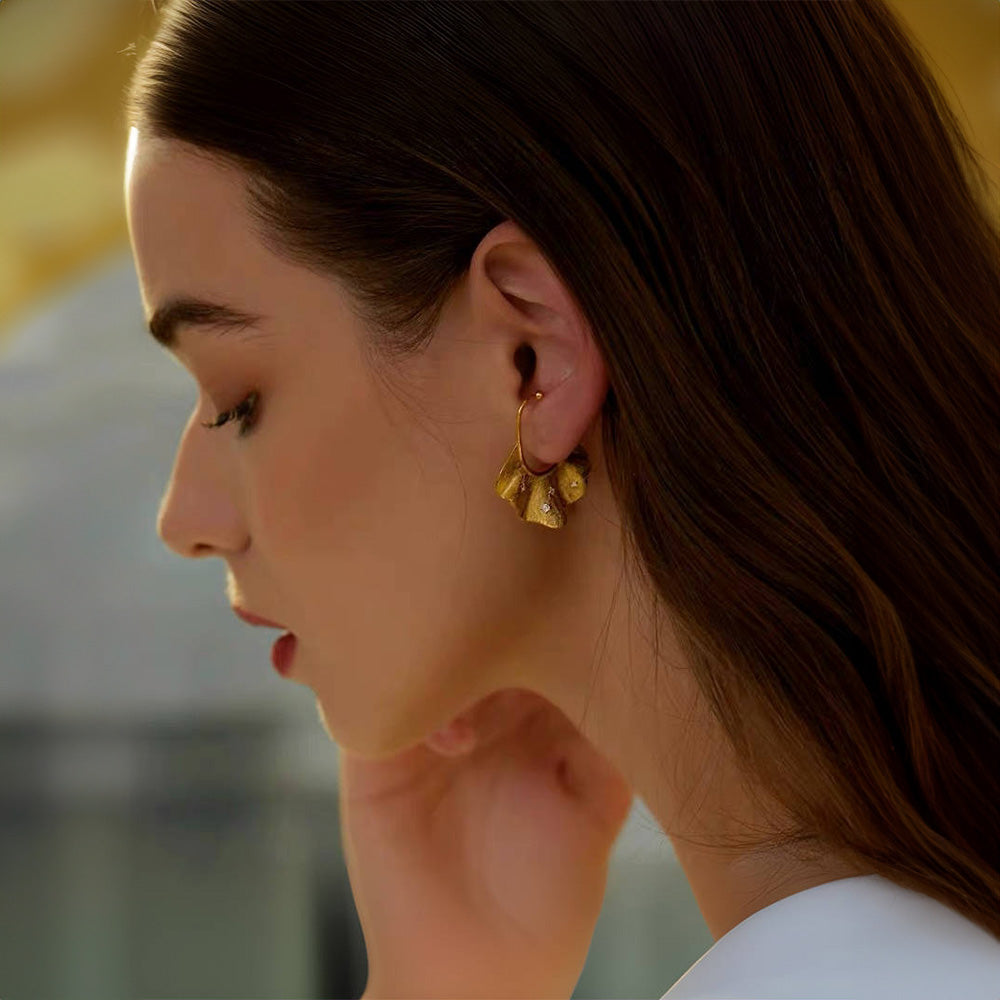 Profile view of a woman wearing a gold Ginkgo Leaf Conch Ear Cuff Earring, with white zircon embellishments, highlighting the unique fan shape of the ginkgo leaf and its sophisticated, nature-inspired design, adding a discreet yet whimsical element to professional attire.