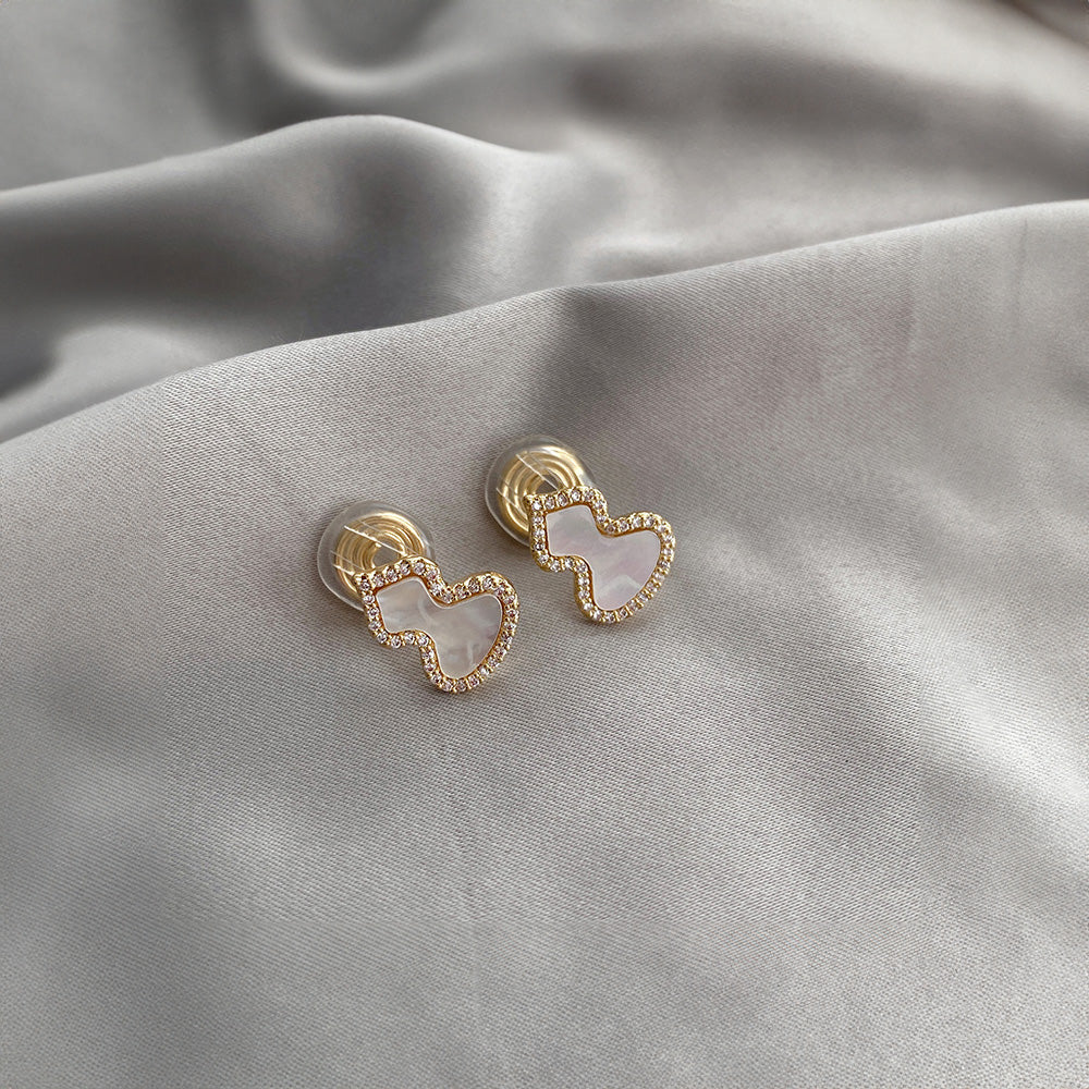 Petite Wulu clip-on earrings in gold and white. Delicate mother-of-pearl gourd with sparkling accents. Gold-tone alloy with secure coil closure. Channel your inner minimalist with a touch of good luck charm. 