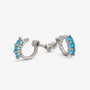A pair of silver huggie hoop earrings with small oval blue gemstones, shown on a light gray background.