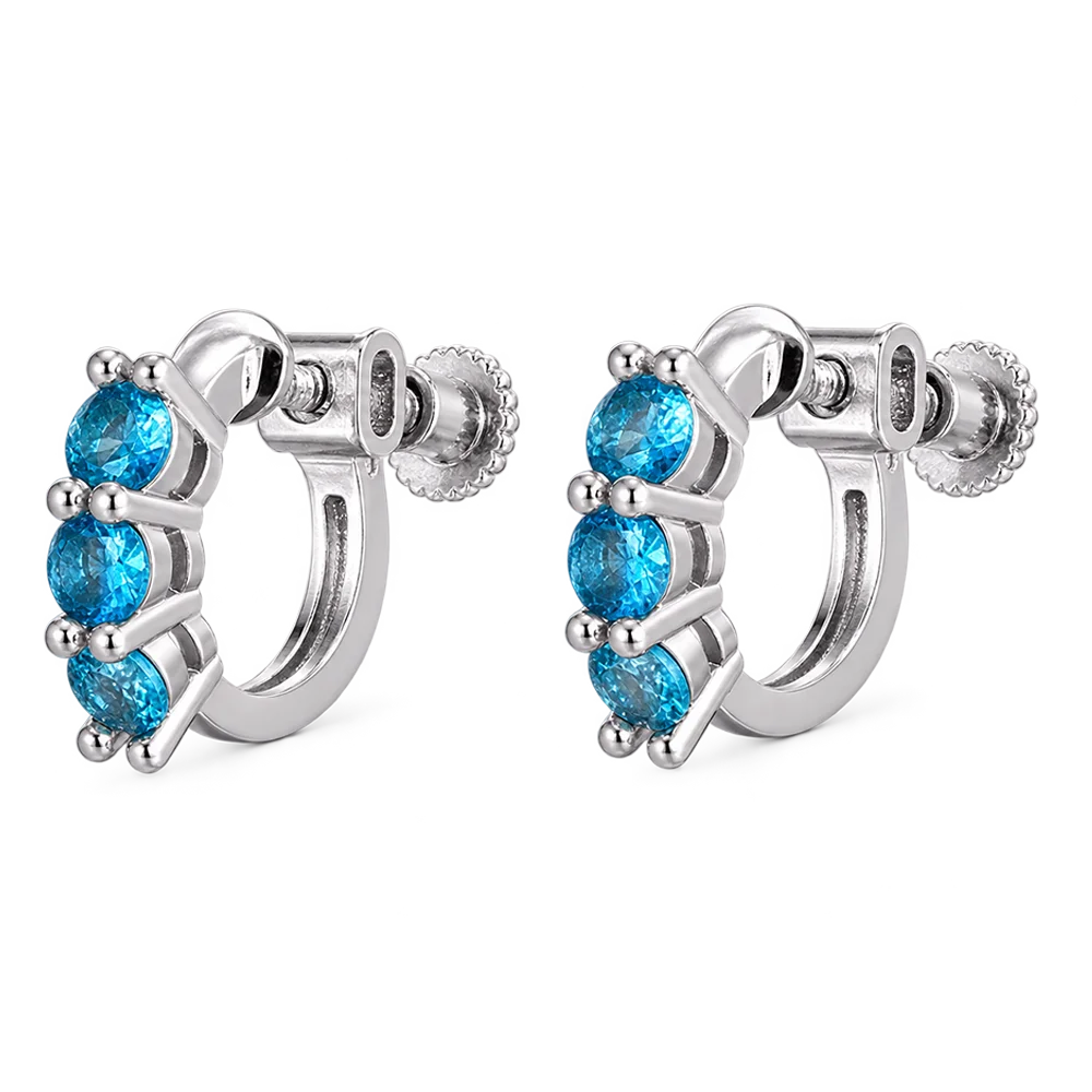 A pair of silver huggie hoop earrings with three faceted blue gemstones in each earring, shown on a plain white background.