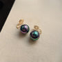 Gros plan sur les boucles d'oreilles à clip Black Pearl, présentant des fausses perles noires de 14 mm avec d'élégants fermoirs dorés.