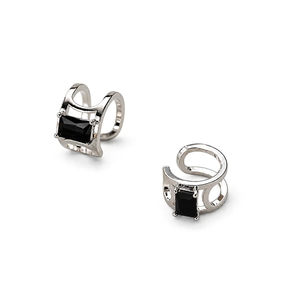Pair of silver earrings with black stones and dangling elements on a white background
