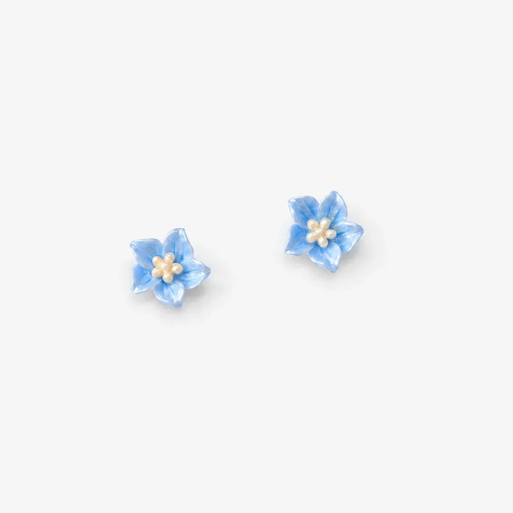 A pair of small light blue flower stud earrings with cream-colored centers, displayed on a clean, light gray background.
