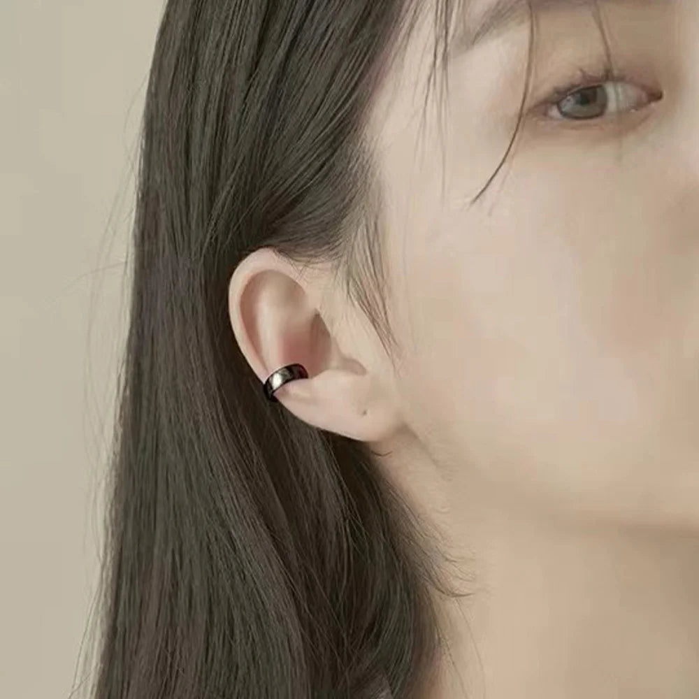 Bold black conch ear cuff side view worn on ear, metallic finish against neutral background
